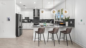 A modern kitchen with a central island, stainless steel appliances, and pendant lighting. - Hi330sd: 5 Bed, Under The Sea, Karaoke (Melbourne Beach)