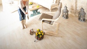 Une pièce spacieuse avec un plafond haut, un banc en bois, une table à manger avec des chaises et un cadre photo fixé au mur.