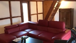 Un salon avec un canapé d’angle rouge, un fauteuil en cuir noir et une petite table.