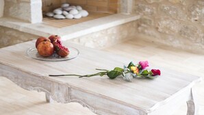 Een gezellige kamer met een houten bank, een witte bank en een tafel met granaatappels en rozen.