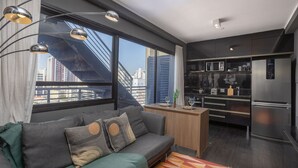Un apartamento moderno con sofá, pequeña cocina y vistas a la ciudad.