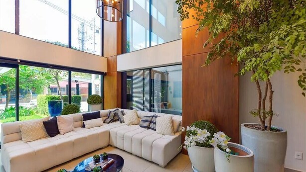 Una sala de estar moderna con un sofá seccional, una mesa de centro y ventanas amplias que ofrecen vistas al exterior.
