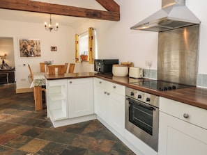 A kitchen with white cabinets, a stainless steel range hood, a built-in oven, and a wooden countertop.