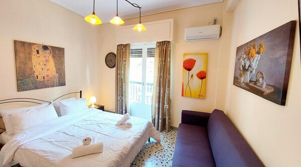 Ein Hotelzimmer mit einem Bett, einer Couch, einem Gemälde und einer Klimaanlage.