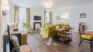 A living room with a yellow sofa, a fireplace, a television, and a dining table with chairs. - Casa Antonia in Lucca (Lucca)