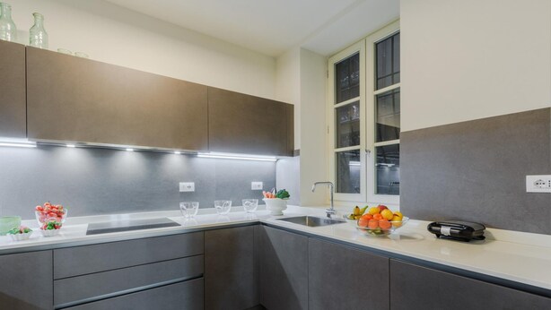 A modern kitchen with grey cabinets, a white countertop, and a window with frosted glass. - Casa Antonia in Lucca (Lucca)