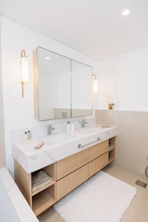 Une salle de bain moderne avec un grand miroir, deux vasques et des meubles en bois.