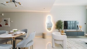 Un salon moderne comprenant un coin repas, un grand miroir, un téléviseur et une plante.