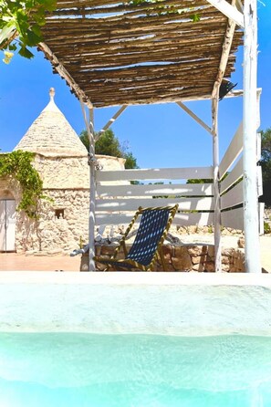 A pool area with a stone building and a pergola structure. - Trullo Solleone con Piscine by Wonderful Italy (Carovigno)