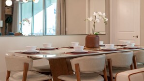 A dining area with a long table set for six, surrounded by six chairs. A large mirror reflects the room, and a potted orchid is placed on the table. - Summer Specials - Super Close to Disney Parks +Restaurants + Heated Plunge Pool (Kissimmee)