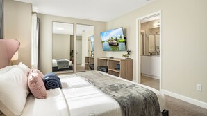 A hotel room with a bed, a TV, a desk, and a bathroom visible through an open door. - Summer Specials - Super Close to Disney Parks +Restaurants + Heated Plunge Pool (Kissimmee)
