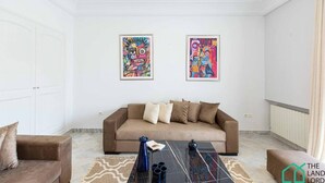 A living room with a brown sofa, two framed abstract paintings, a coffee table, and a patterned rug.