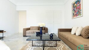 A living room with a glass coffee table, two sofas, a patterned rug, and a door in the background.