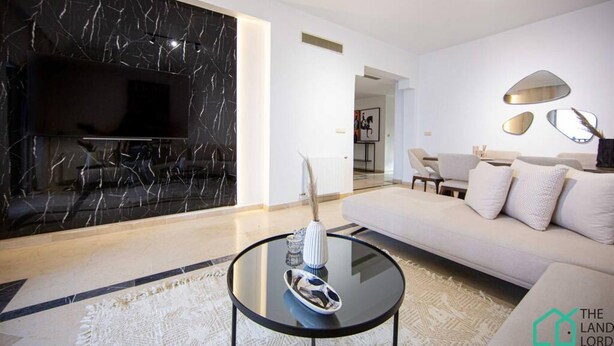 Una sala de estar moderna con un televisor de pantalla plana, una mesa de centro redonda y un sofá.