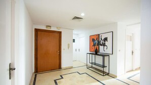 Un pasillo con una puerta de madera, una consola negra con obras de arte y un piso estampado.