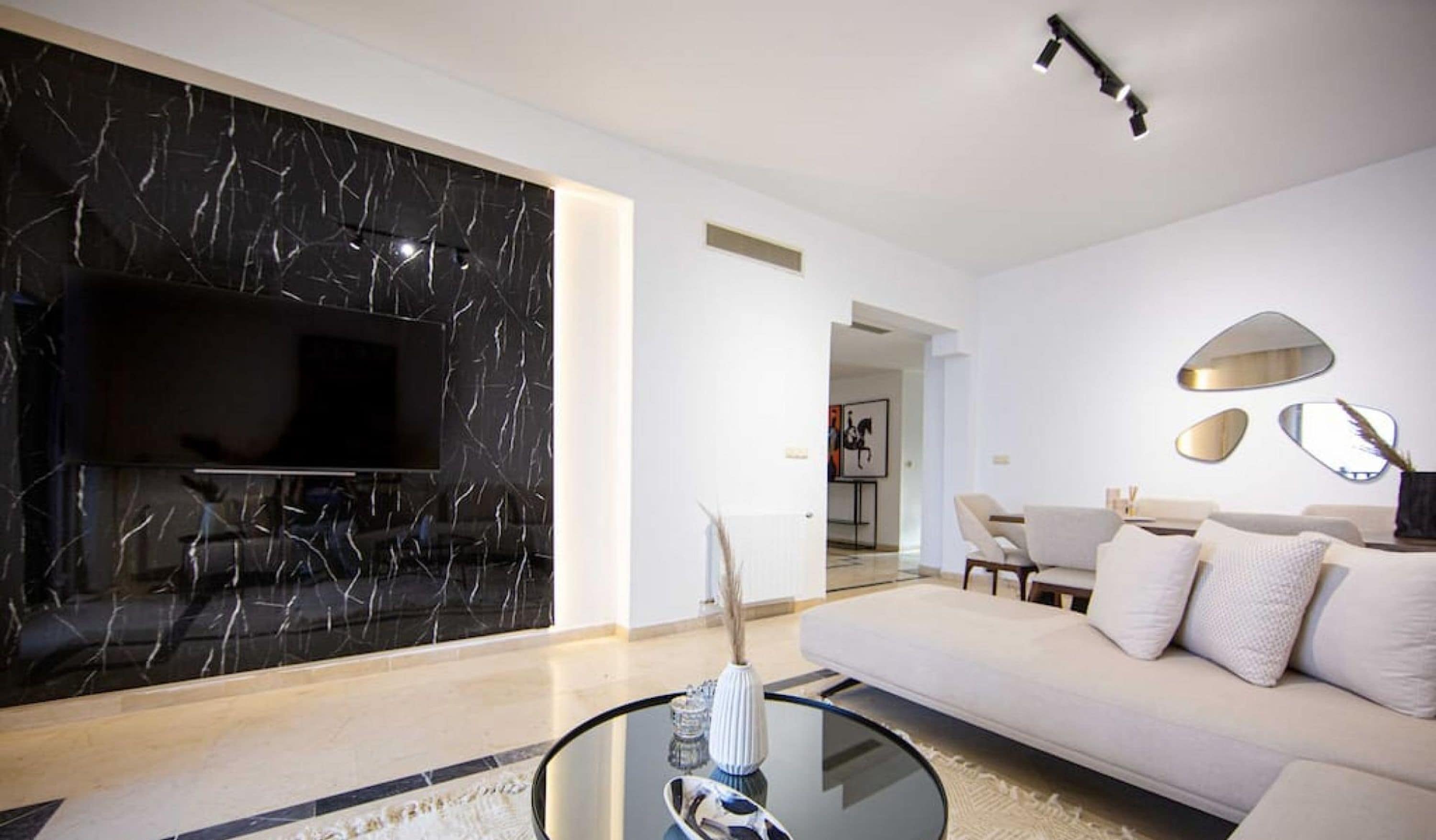 A modern living room with a flat-screen TV, a sofa, a coffee table, and a decorative vase.