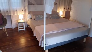 A four-poster canopy bed with a white canopy, two bedside tables with lamps, and a chair. - A LOU, A haven of peace with its private jacuzzi for nature lovers ! (Le Diamant)