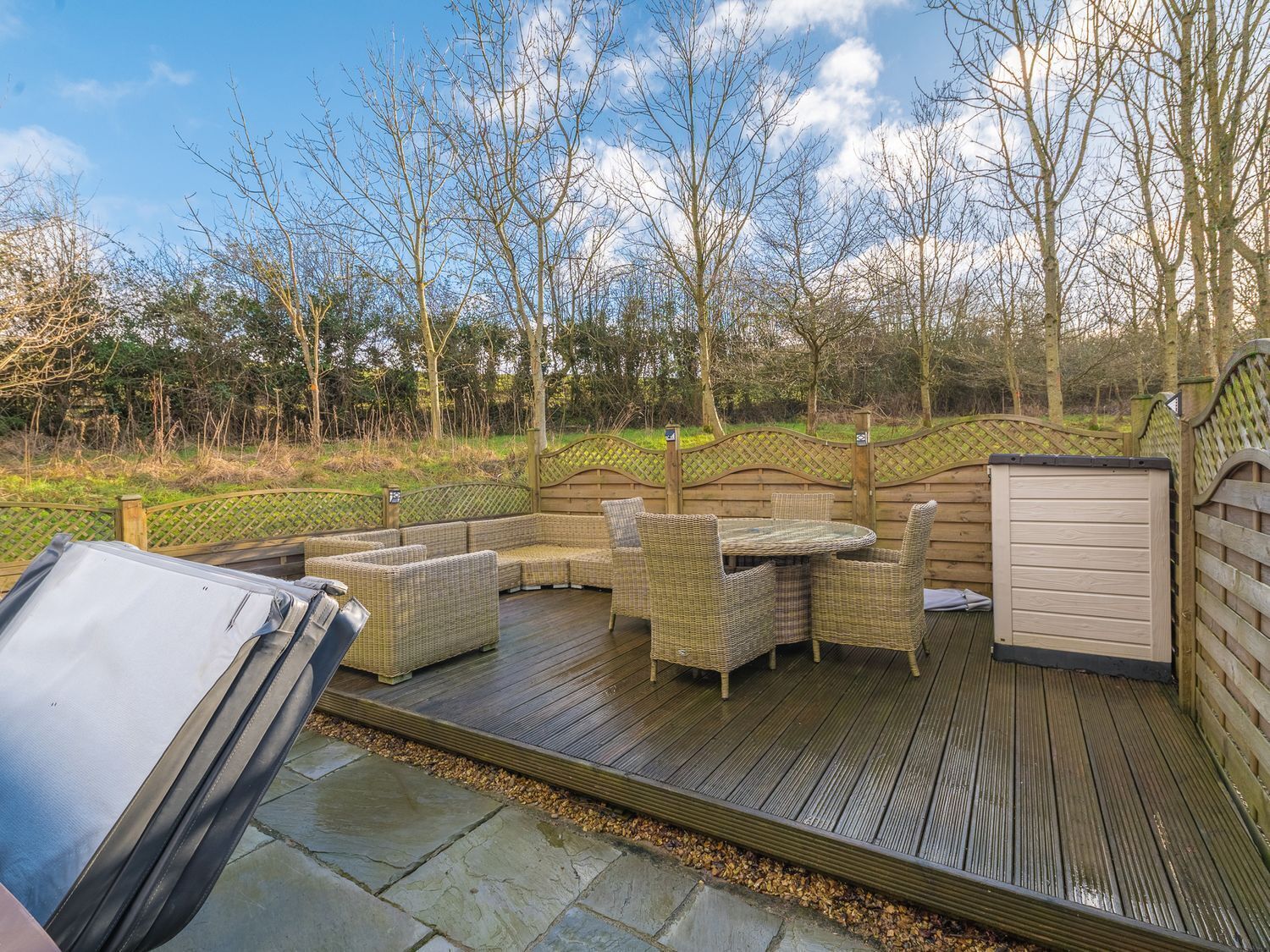 An outdoor patio with wicker furniture, a barbecue grill, and a wooden deck.