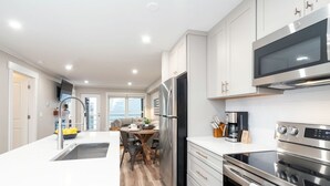 A modern kitchen with white cabinets, stainless steel appliances, and a large window. - Perfect Location! King Bed, Full Kitchen, Walk To Gondola 2 Bedroom Condo by RedAwning (Telluride)