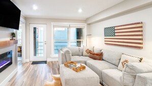 A modern living room with a sectional sofa, a fireplace, and a large American flag on the wall. - Perfect Location! King Bed, Full Kitchen, Walk To Gondola 2 Bedroom Condo by RedAwning (Telluride)