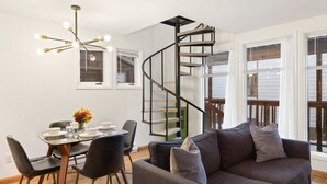 A modern living room with a spiral staircase, a dining area with a glass table, and a sofa with cushions. - Comfort, Style, Short Walk To Town Park & Gondola 1 Bedroom Condo by RedAwning (Telluride)