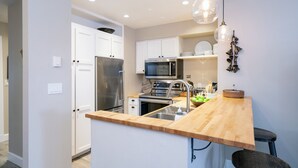 A modern kitchen with stainless steel appliances, a wooden countertop, and pendant lighting. - Ski In/out In Town! Ski Area Views, Fireplace, Hot Tub 2 Bedroom Condo by RedAwning (Telluride)