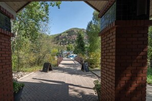 Pathway leads to a scenic mountain view, framed by lush greenery and trees.