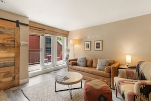 Un salon comprenant un canapé, un fauteuil, une table basse et une porte coulissante.