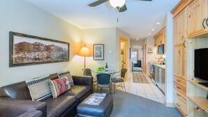 A modern living room with a leather sofa, a coffee table, a ceiling fan, and a dining area with chairs and a table. - Clean, Cozy Riverside Condo, Walk Everywhere @ Viking Lodge 212 1 Bedroom Condo by RedAwning (Telluride)