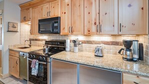 A kitchen with wooden cabinets, a microwave, a stove, a toaster, and a coffee maker. - Clean, Cozy Riverside Condo, Walk Everywhere @ Viking Lodge 212 1 Bedroom Condo by RedAwning (Telluride)