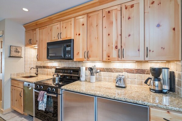 A kitchen with wooden cabinets, a microwave, a stove, a toaster, and a coffee maker. - Clean, Cozy Riverside Condo, Walk Everywhere @ Viking Lodge 212 1 Bedroom Condo by RedAwning (Telluride)