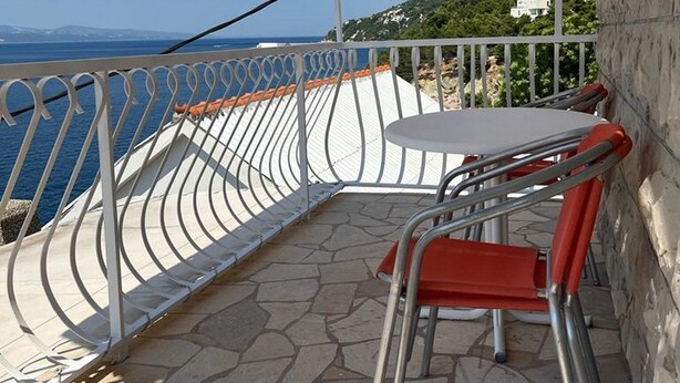 A terrace with a table and chairs, overlooking a coastal view. - Apartments Leut (Omis)