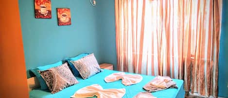 Una habitación con una cama, aire acondicionado de pared y dos cuadros.