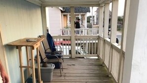 Eine überdachte Holzterrasse mit Geländer, Tisch und Stühlen.