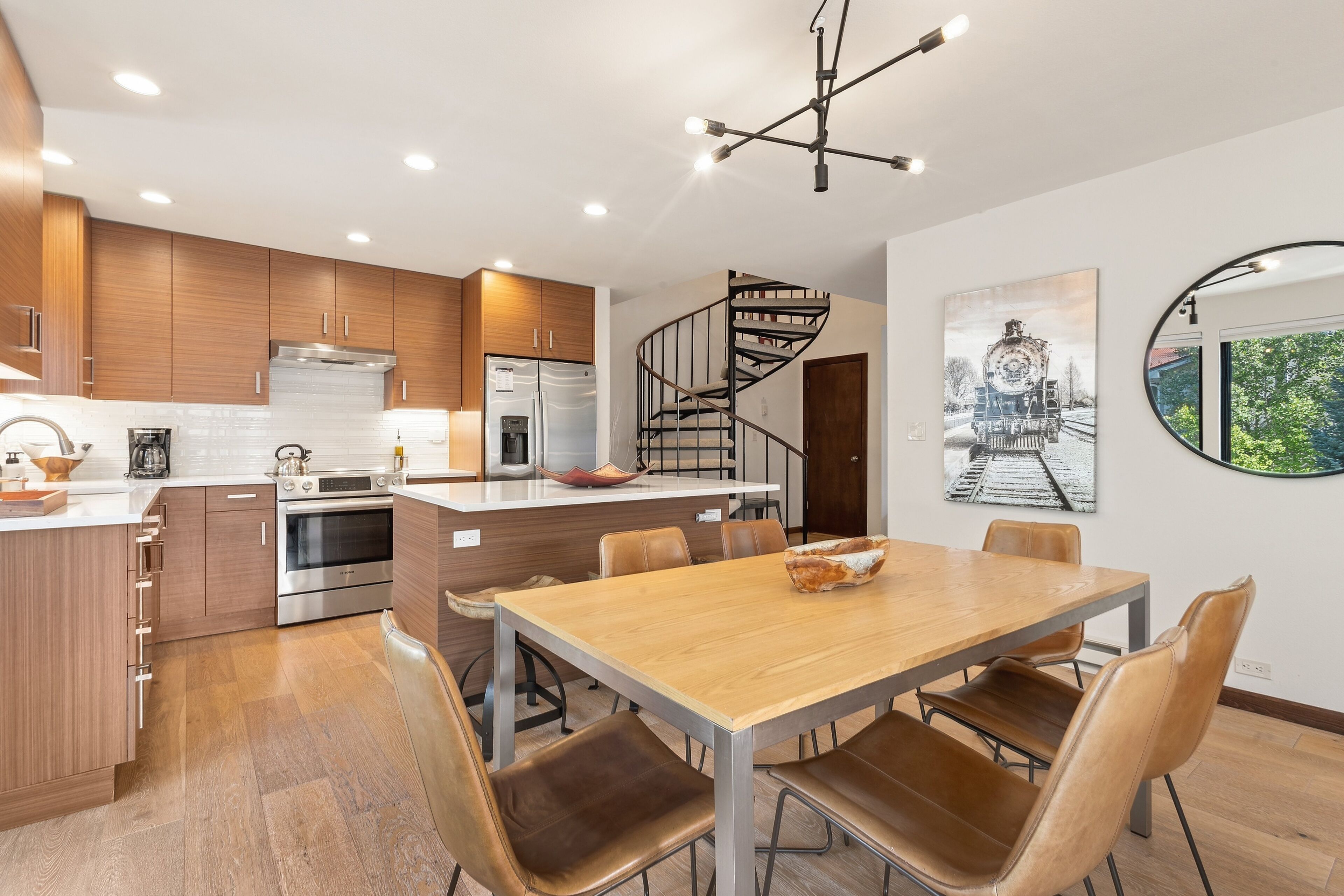 A modern kitchen with wooden cabinets, stainless steel appliances, and a central island with seating.