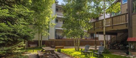 A courtyard with a picnic table, chairs, and bicycles.