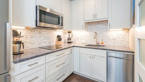 A modern kitchen with white cabinets, a Bosch microwave, a coffee maker, and a dishwasher. - Walk To Ski, Stylish & Bright! Ground Floor, Hot Tub, Pool 1 Bedroom Condo by RedAwning (Telluride)