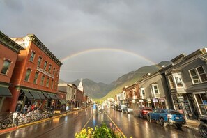 A street with buildings, a rainbow, and mountains in the background. - Walk To Ski, Stylish & Bright! Ground Floor, Hot Tub, Pool 1 Bedroom Condo by RedAwning (Telluride)