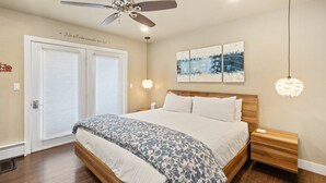 A bedroom with a bed, a ceiling fan, a nightstand, and artwork on the wall. - Walk To Ski, Stylish & Bright! Ground Floor, Hot Tub, Pool 1 Bedroom Condo by RedAwning (Telluride)