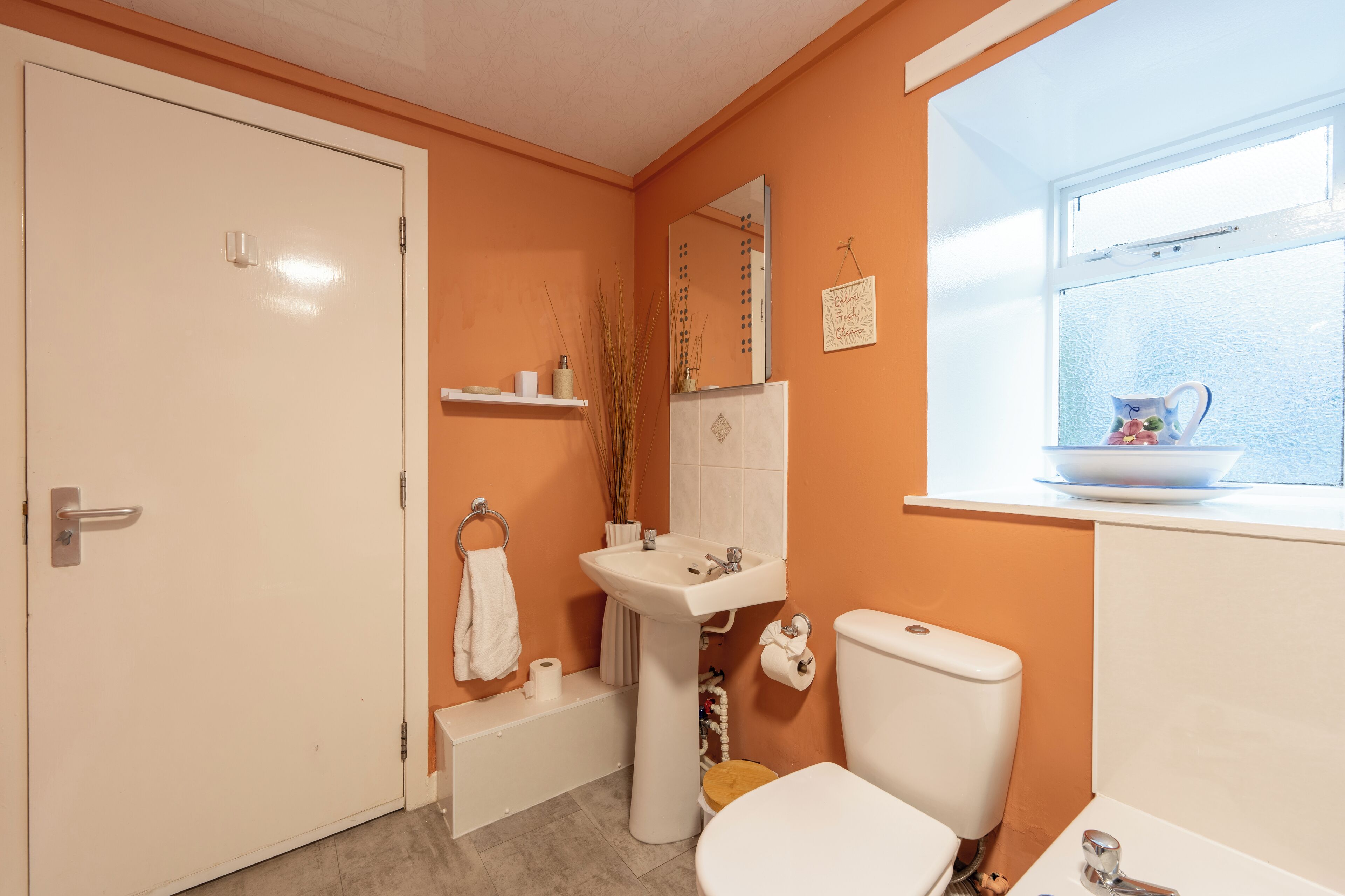 A bathroom with a toilet, sink, and window.