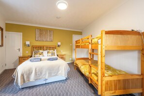 Een kamer met een stapelbed, een enkel bed en een vloerbedekking.