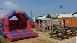 An inflatable Spider-Man bouncy castle, picnic tables, and a playground with a slide. - Remarkable Caravan in Abergele Towyn (Abergele)