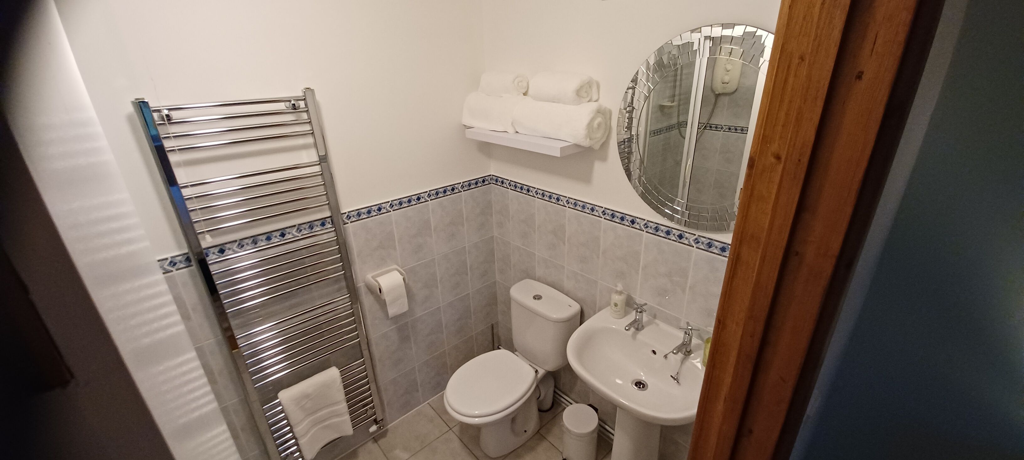 A compact bathroom with a toilet, sink, and towel rack.