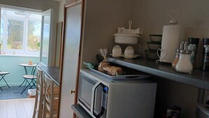 A kitchen with a microwave, a shelf with kitchenware, and a view of the outside. - Relax With Amazing Views! 1-bed Studio in Tegryn (Llanfyrnach)