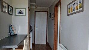 A hallway with a door, framed pictures on the walls, and a small table with books and a board. - Relax With Amazing Views! 1-bed Studio in Tegryn (Llanfyrnach)