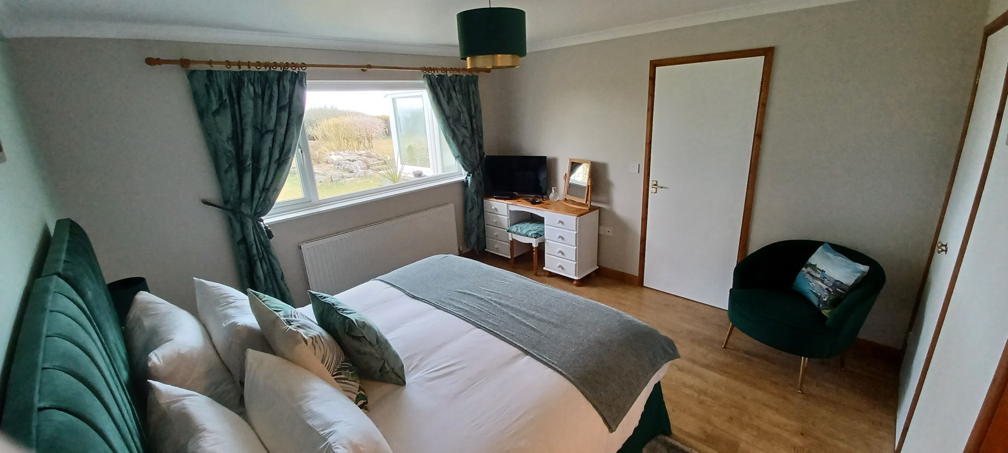 A bedroom with a bed, a desk, a chair, a TV, and a wardrobe.