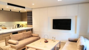 A modern living room with a sofa, a coffee table, and a TV mounted on the wall. - Luxurious Apartment in Acropolis (Athens)