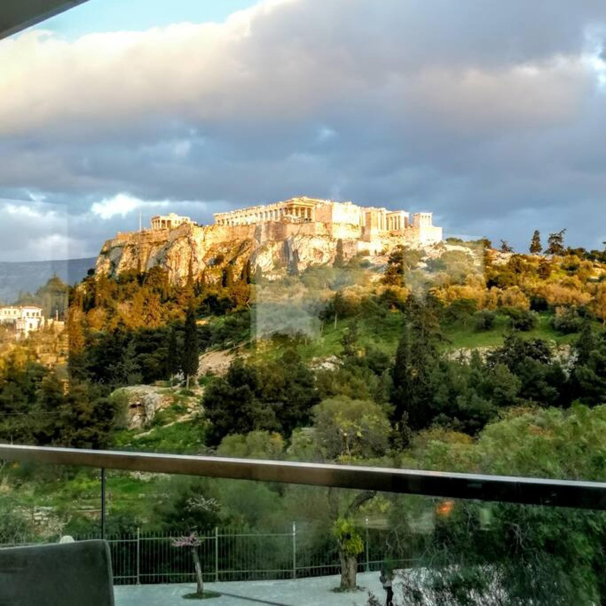 A view of a historic building on a hill, with a balcony in the foreground.