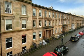 A row of terraced houses with a uniform architectural style, featuring evenly spaced windows and a consistent facade. - Walk Anywhere From This Cosy Central Flat (Glasgow)