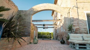 An outdoor courtyard with a stone archway, brick walls, and potted plants. - Villa Rustica 8 (Ravenna)